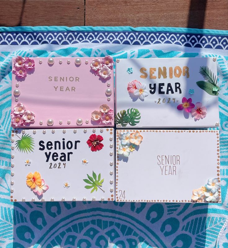 four different colored cards on a blue and white cloth with flowers, leaves and letters