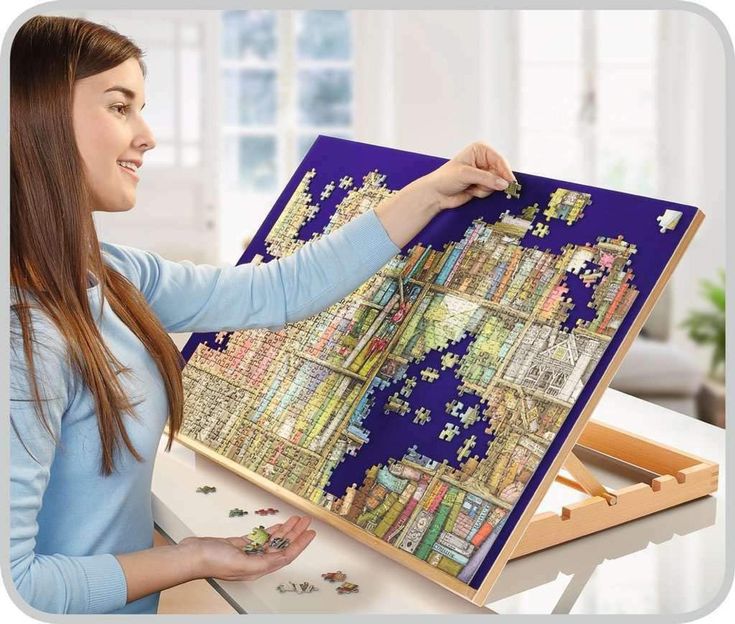 a woman is holding up a puzzle on a easel with the city map in it