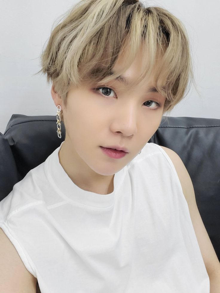 a person sitting on top of a couch wearing a white shirt and gold earring