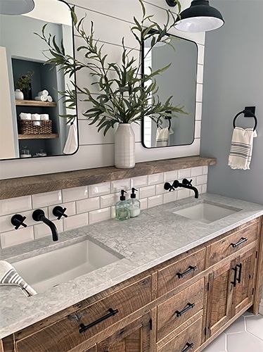 a bathroom with two sinks, mirrors and plants in vases on the counter top