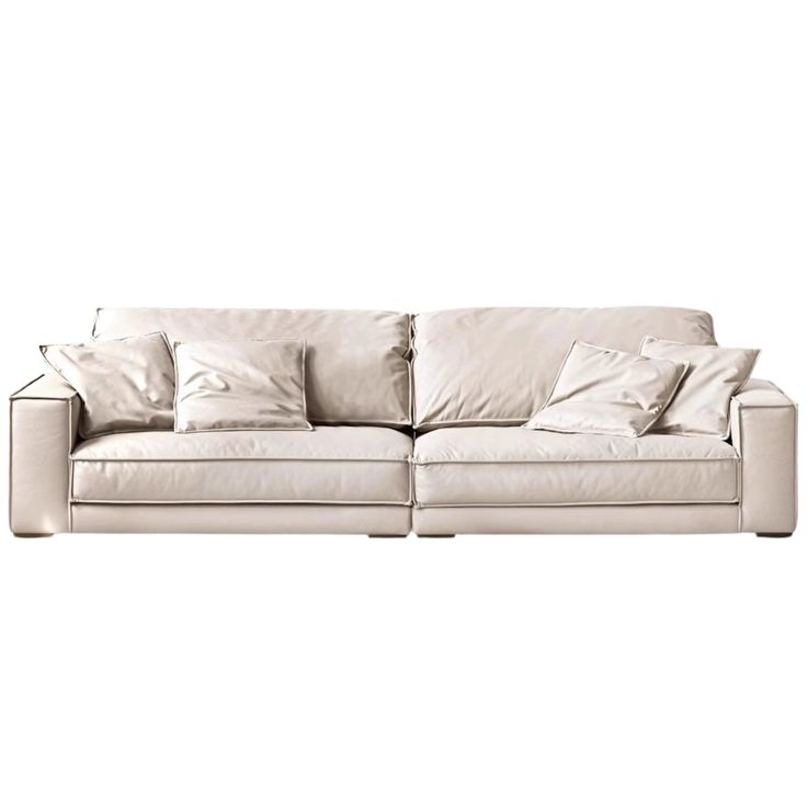 a white couch with lots of pillows on it's back and armrests