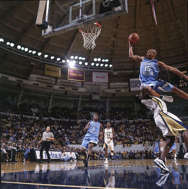 a basketball player jumping up to dunk the ball in front of other players and fans