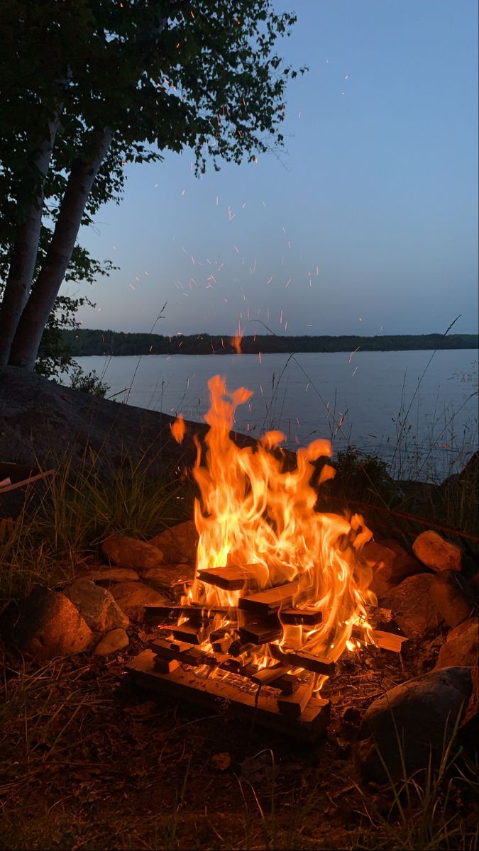 a campfire is lit up by the water