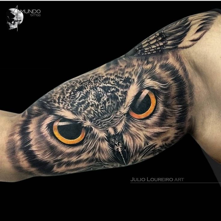 an owl tattoo with orange eyes on the arm