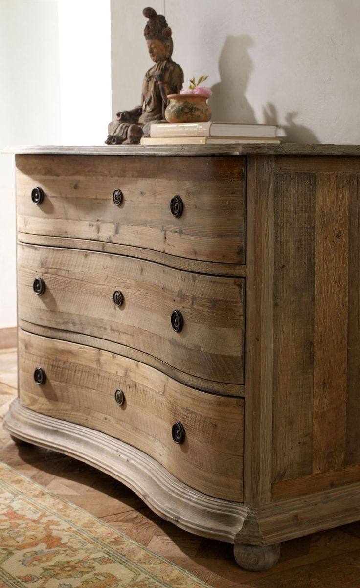 an old wooden dresser with drawers in a room next to a wall and a cat figurine on top of it