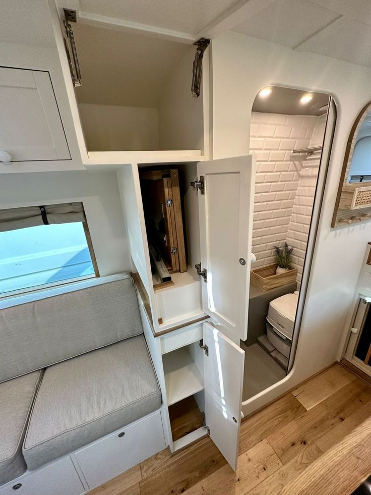 the inside of a small rv with a couch, mirror and storage compartment in it