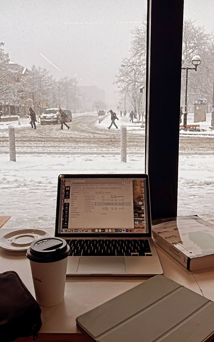 an open laptop computer sitting on top of a desk next to a cup of coffee