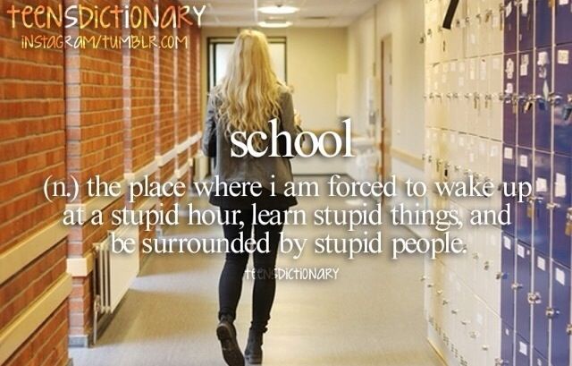 a woman walking down a hallway next to lockers with writing on them that reads school