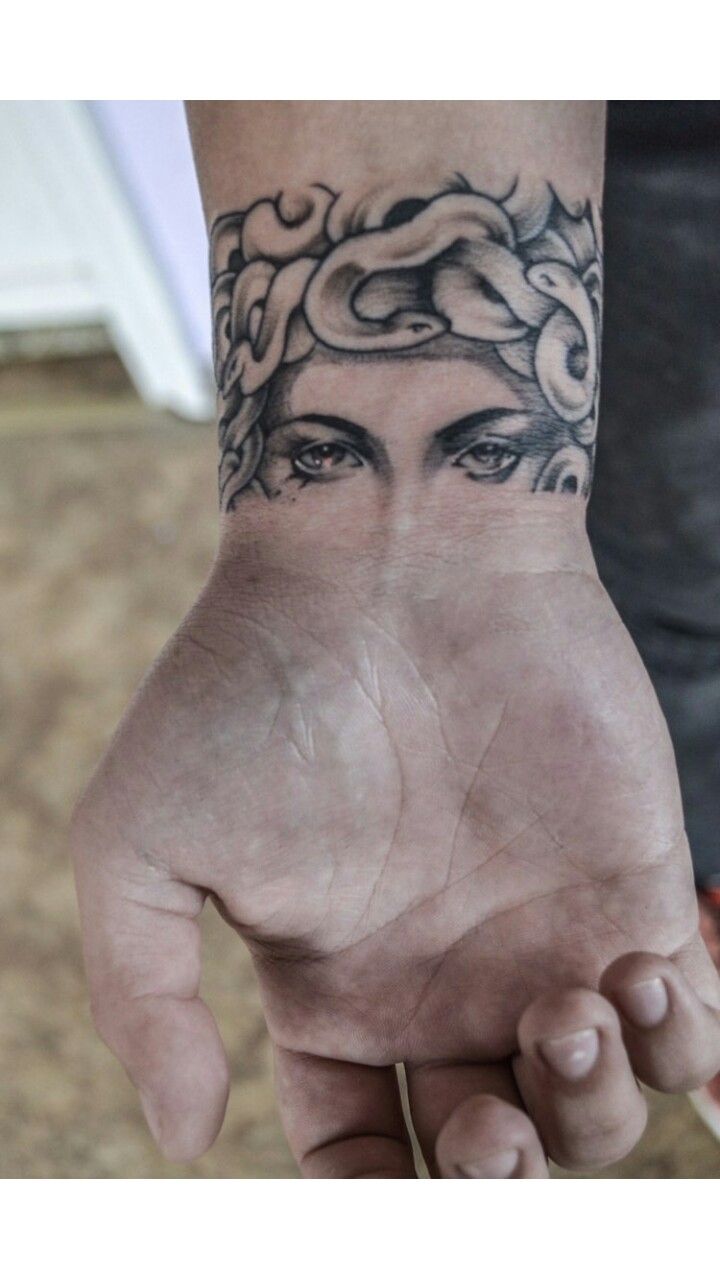 a woman's hand with a tattoo on it and her face in the middle