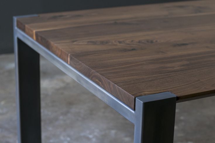 a wooden table sitting on top of a cement floor next to a metal framed wall