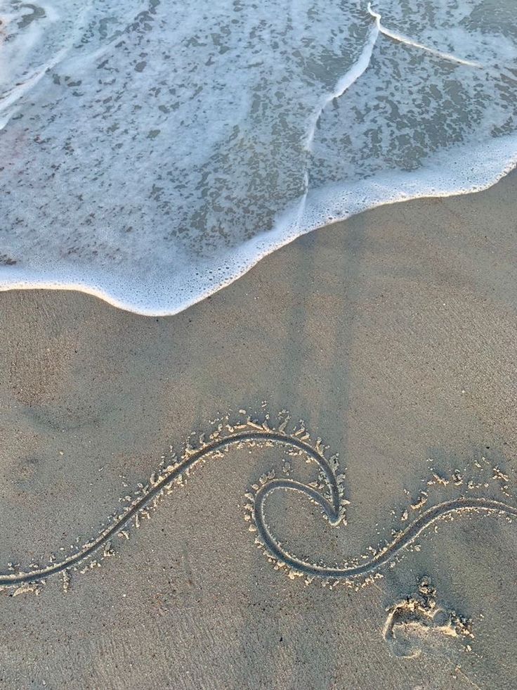 a wave is drawing in the sand at the beach