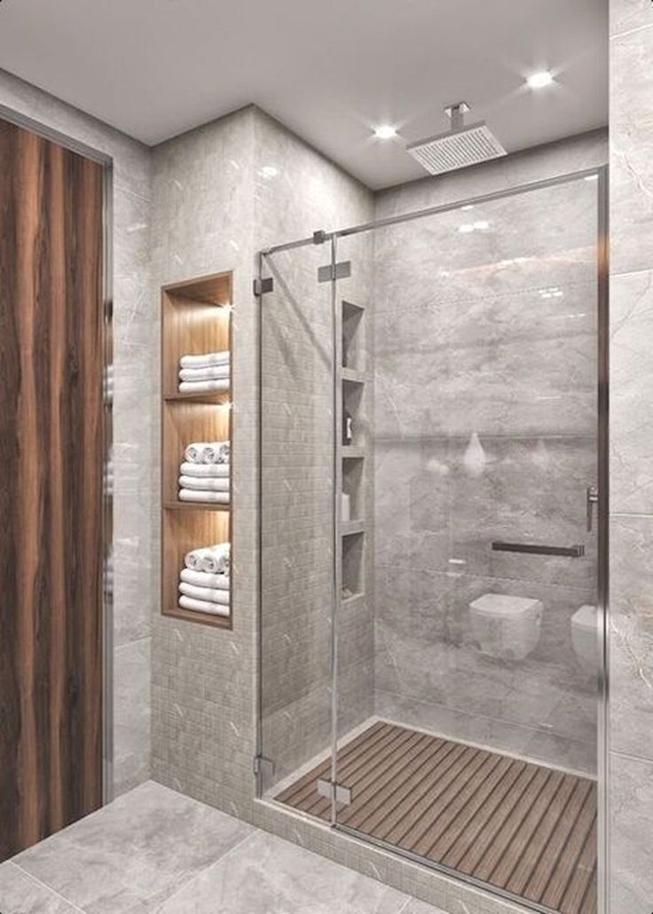 a bathroom with a walk in shower next to a wooden door and white towels on the shelves