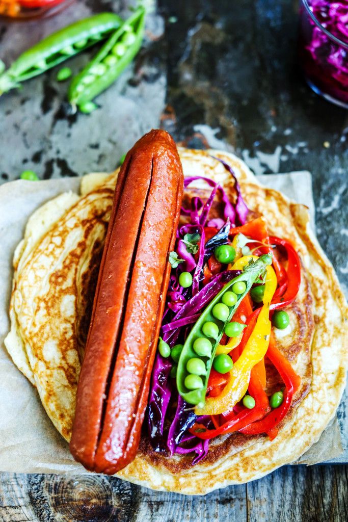 a hot dog on top of a tortilla covered in veggies and beans