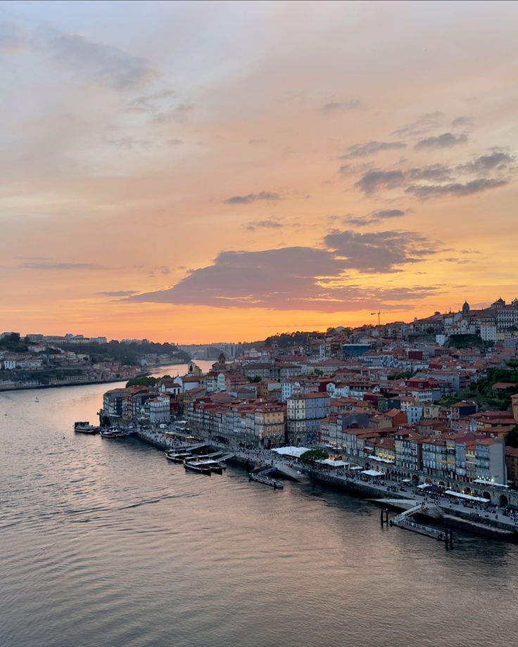 a river that has boats in it and some buildings on the other side with sunset