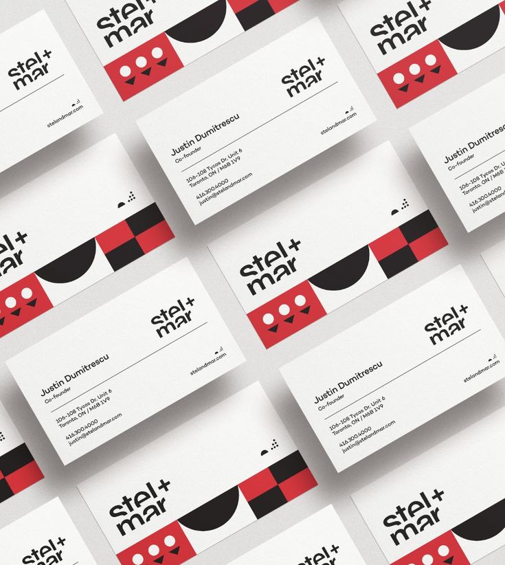 many business cards are stacked on top of each other, with black and red designs