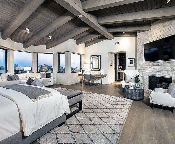 a large bedroom with high ceilings and hardwood floors, along with a fireplace in the center