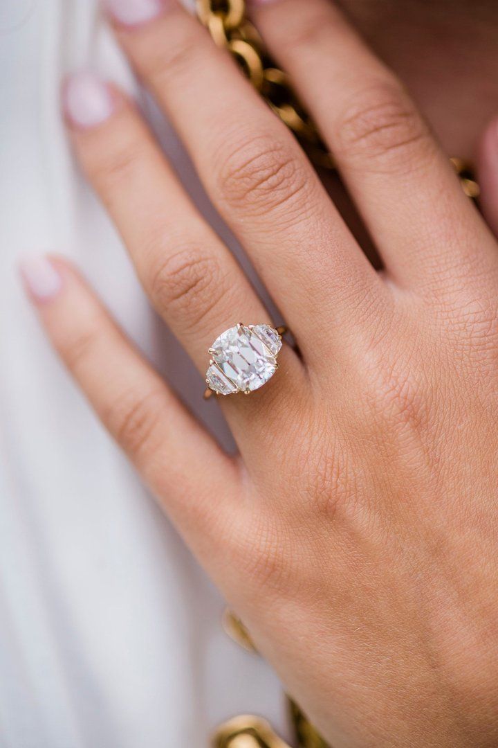 a woman's hand with a diamond ring on top of her finger and gold chains around it