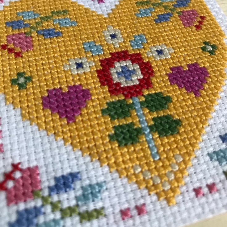 a cross - stitch pattern with flowers and hearts on the bottom is shown in yellow