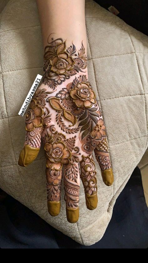 a woman's hand with henna tattoos on her arm and hands, all decorated with flowers