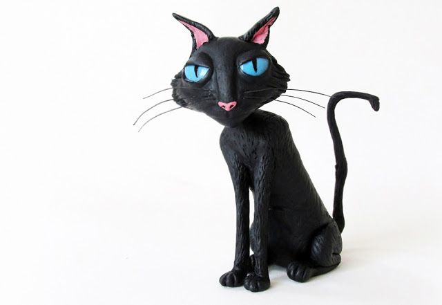 a black cat figurine with blue eyes on a white background