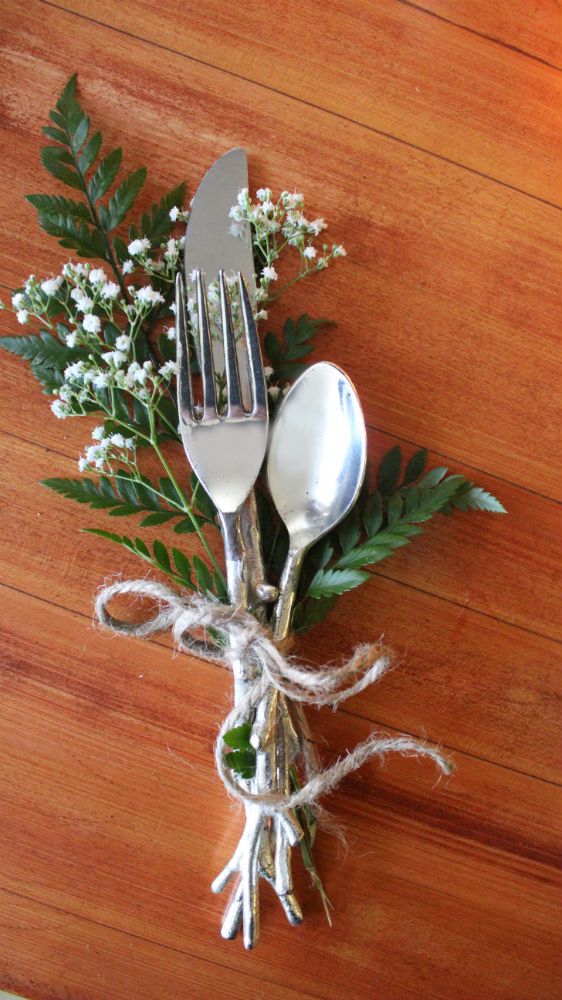 two forks and spoons tied together with twine on a wooden table next to baby's breath flowers