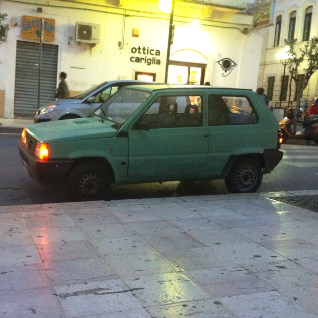 a green car is parked on the side of the street