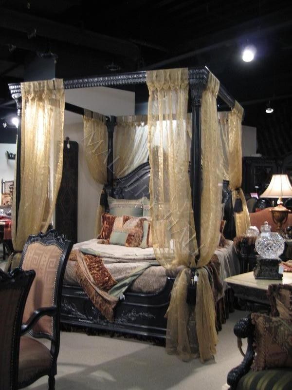 a bed and some chairs in a room with curtains on the ceiling, and lights hanging from the ceiling