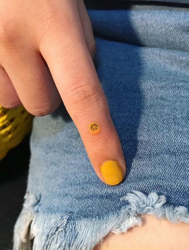 a person pointing to the left side of their jeans with a smiley face on it