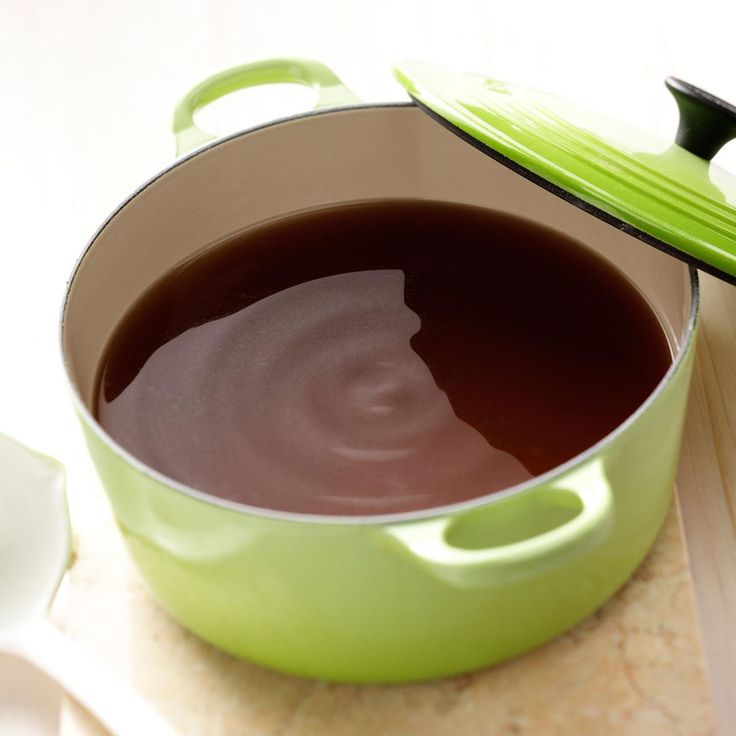 a green pot filled with liquid next to a spoon