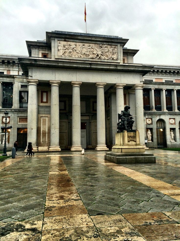 an old building with columns and statues in front