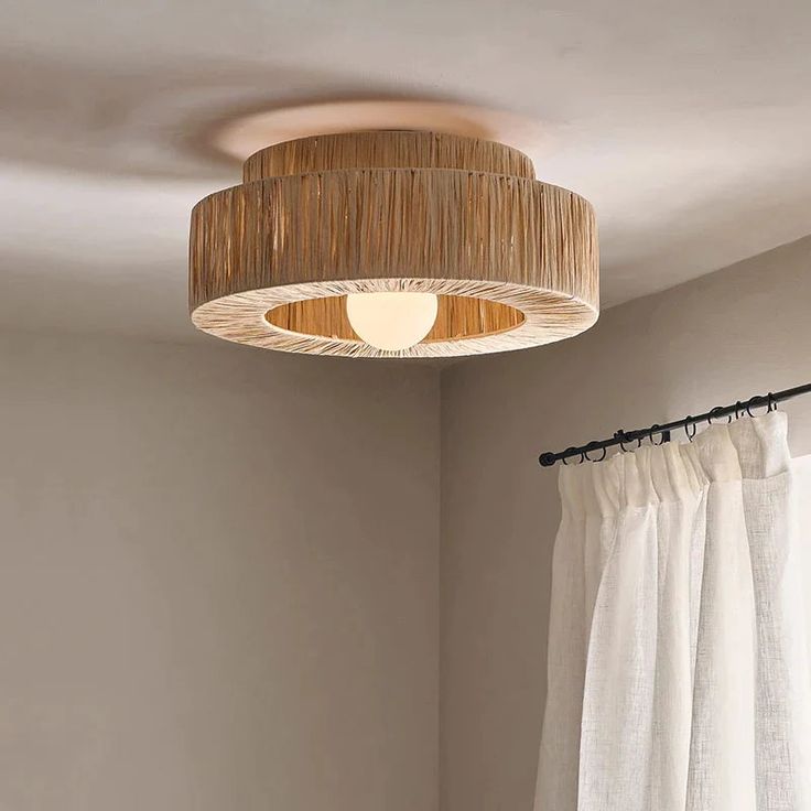 a light that is on above a bed in a room with curtains and drapes