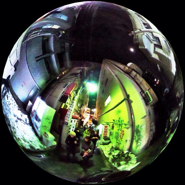 a fish eye view of people walking down the street in front of a building at night