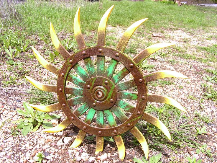 a metal sunflower sitting on top of a grass covered field