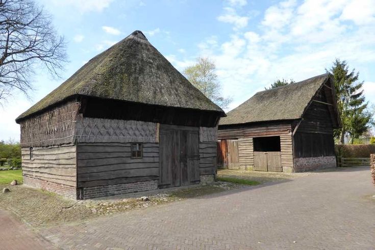 an old wooden building with thatched roof and brick walkway leading up to the entrance