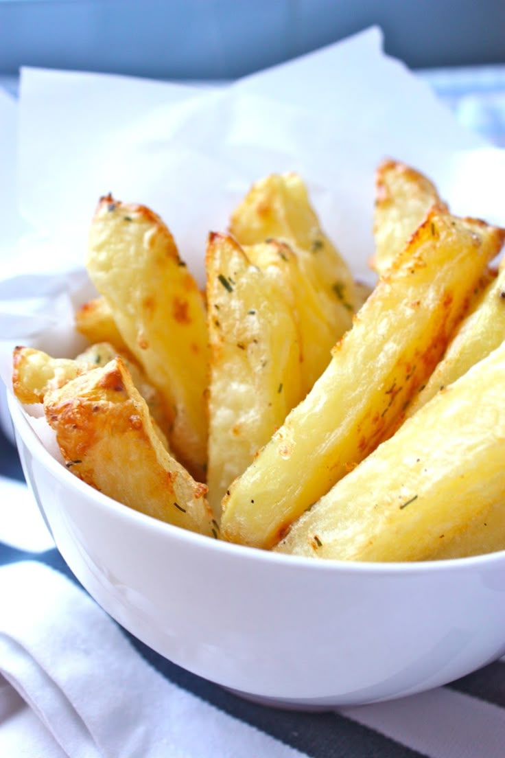 a white bowl filled with cheesy fries on top of a blue and white table cloth