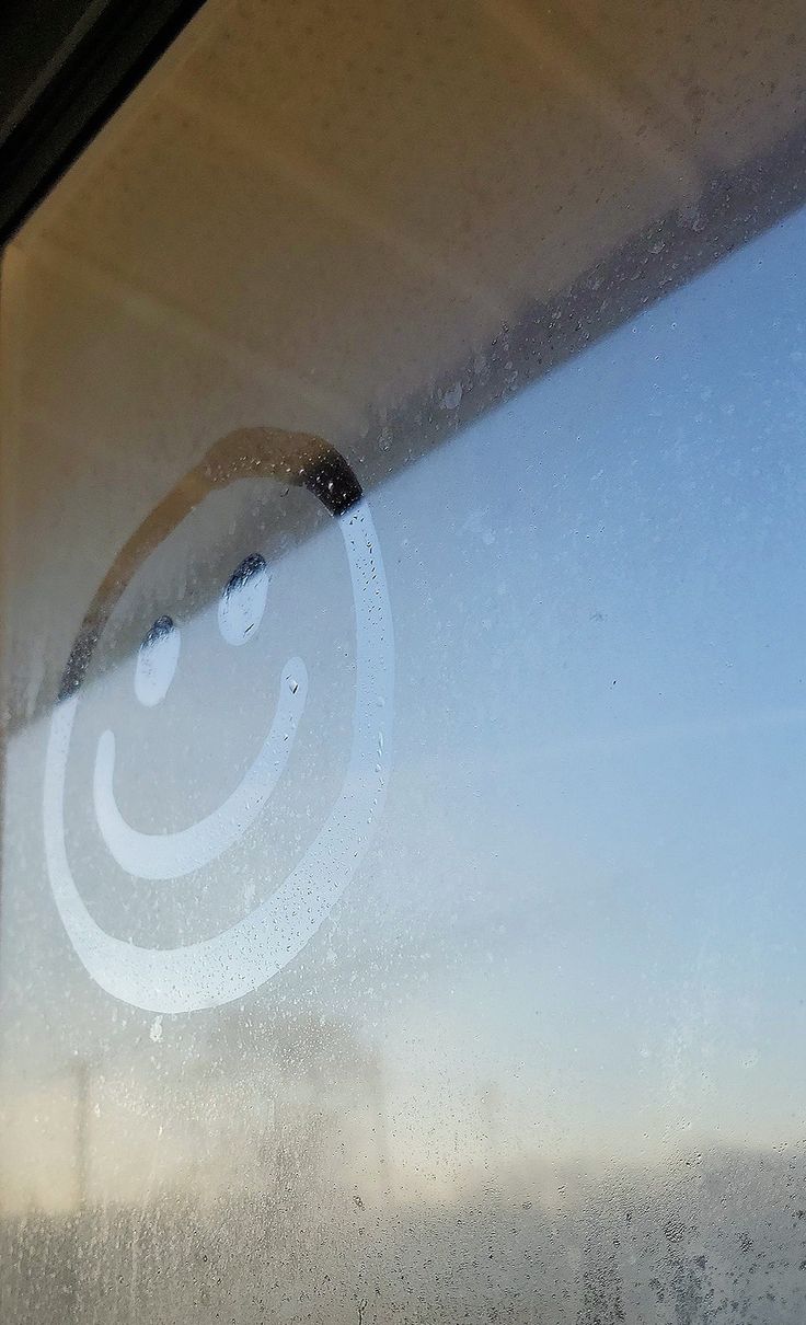 a smiley face drawn on the side of a window with condensation coming from it