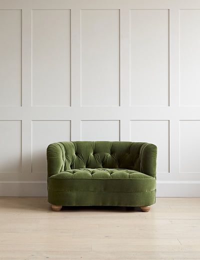 a green chair sitting on top of a hard wood floor next to a white wall