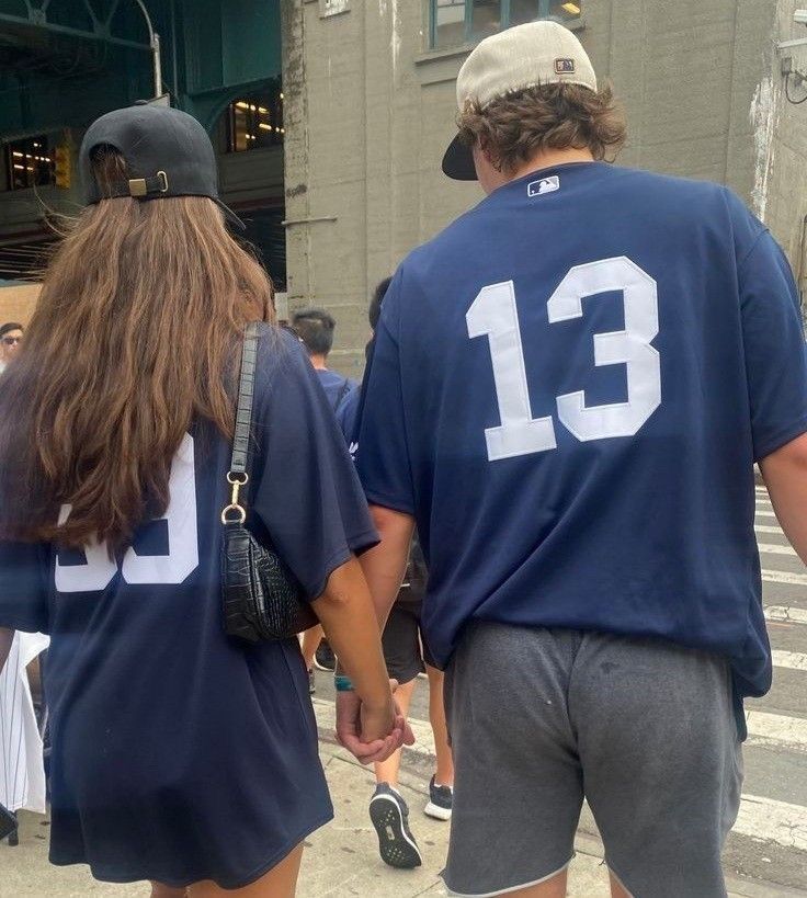 a man and woman walking down the street wearing shirts with number 13 on it's back