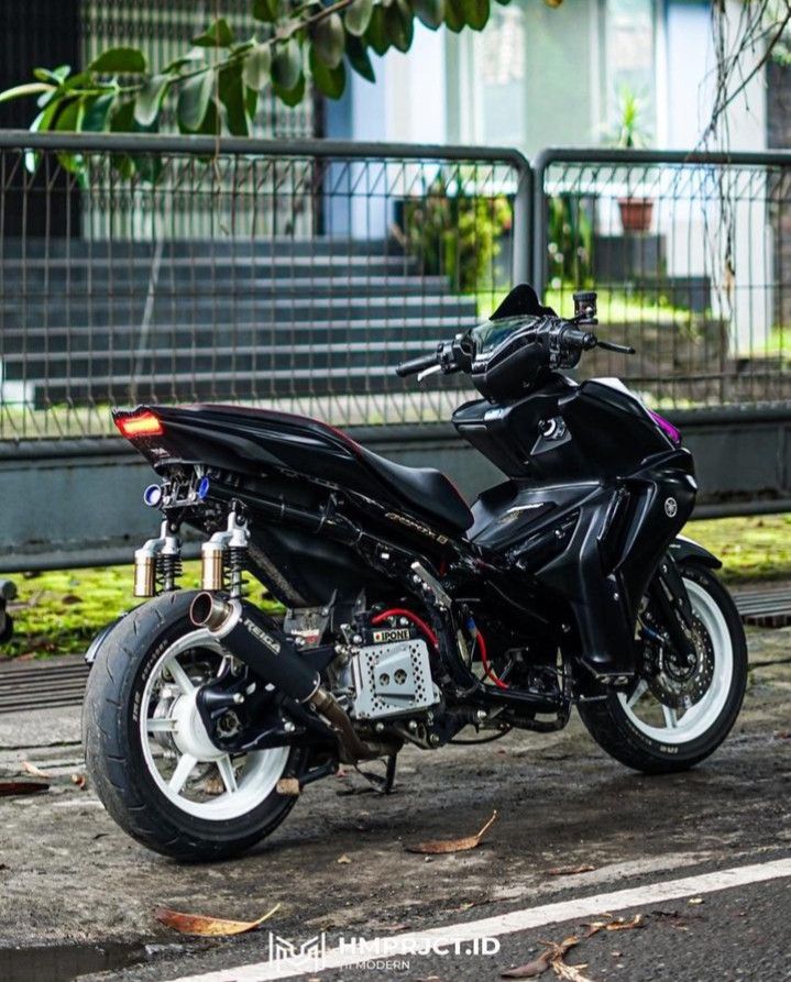 a black motorcycle parked in front of a metal fence on the side of a road