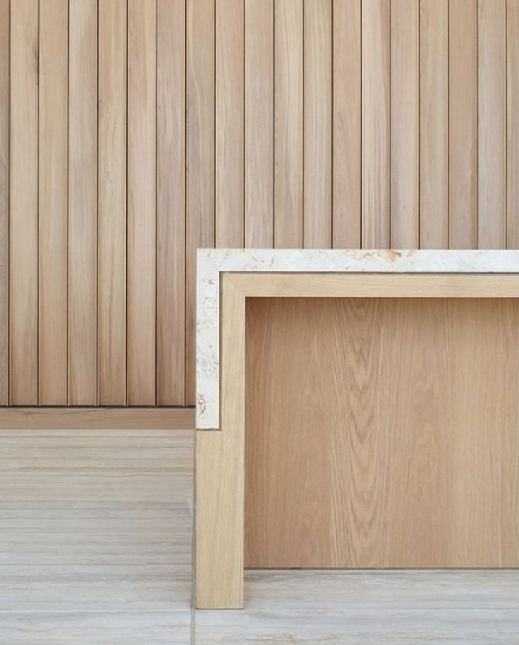 an empty wooden table sitting on top of a hard wood floor next to a wall