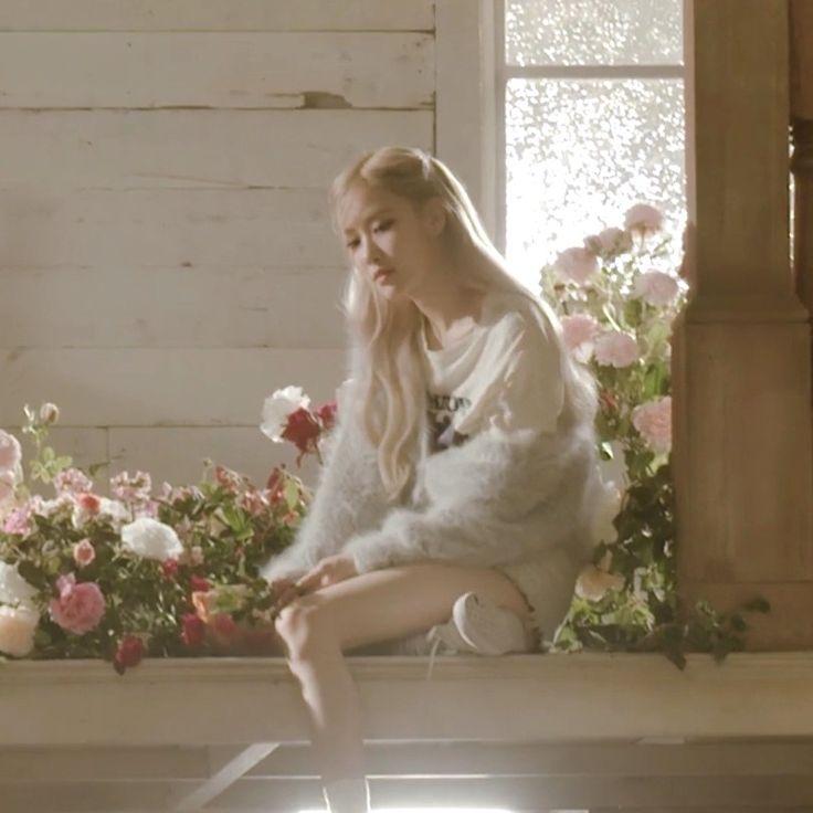 a woman sitting on top of a window sill next to flowers