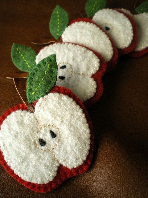 there are four apples made out of felt with leaves on the top one is red and white