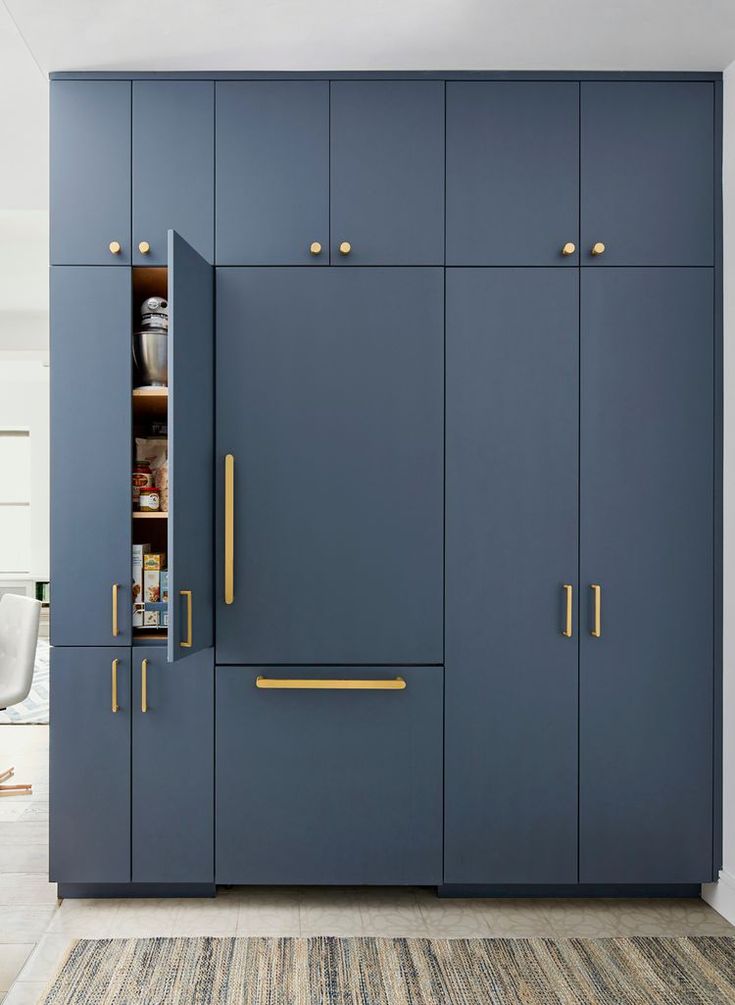 a kitchen with blue cabinets and gold handles on the doors, along with a rug