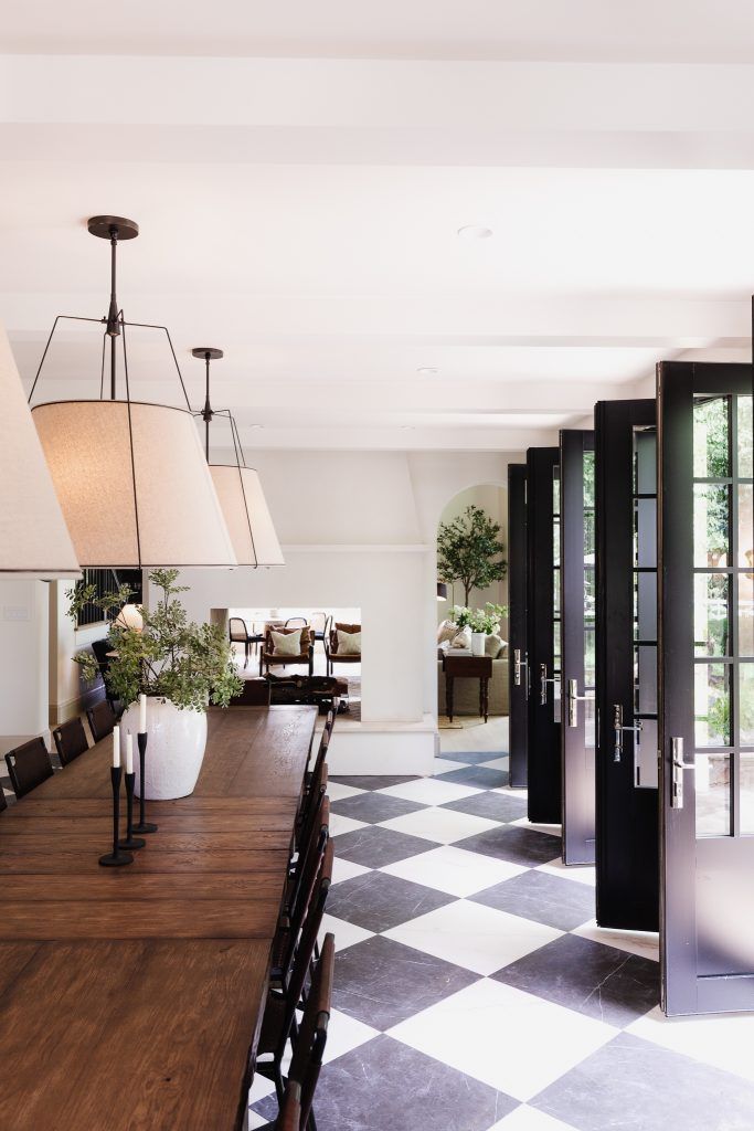 a dining room table with chairs and lamps on it in front of a checkered floor