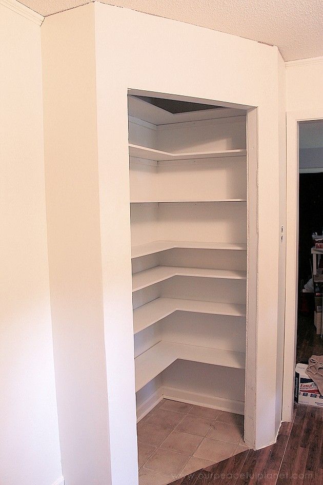 an empty room with white shelving in the corner and hard wood flooring on the other side