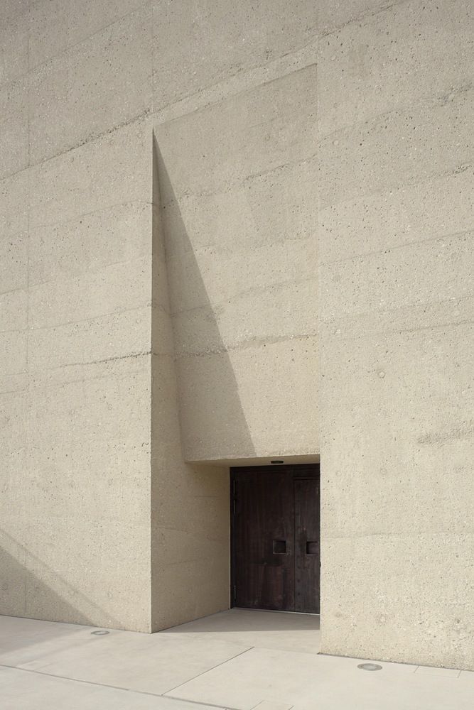 an open door in the side of a large building with concrete walls and flooring