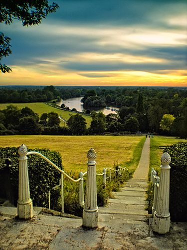 the stairs lead up to an overlook overlooking a grassy field and river in the distance