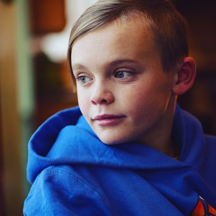 a young boy wearing a blue hoodie looking at the camera with a serious look on his face