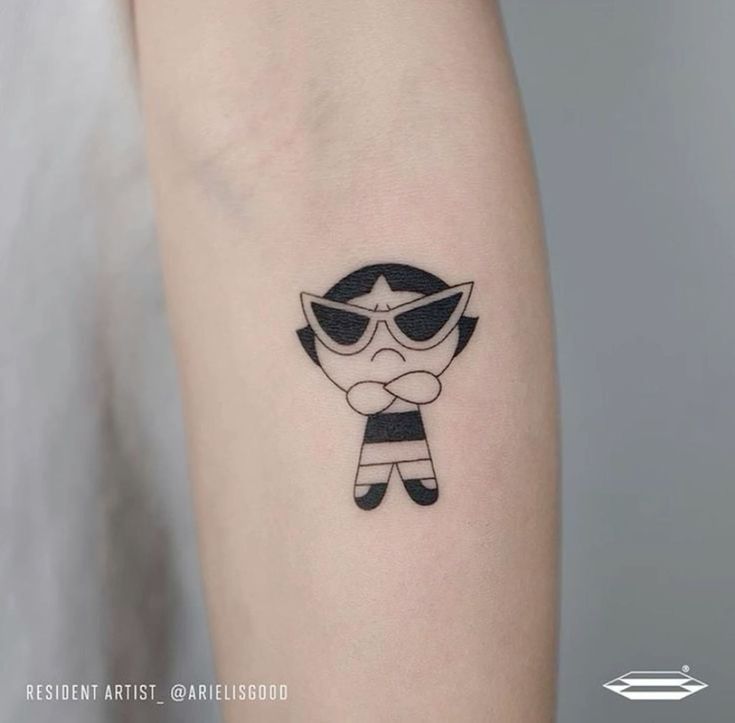 a woman's arm with a small cartoon character tattoo on the left inner arm