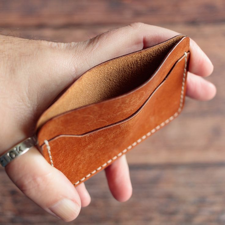 a hand holding an empty wallet on top of a wooden table